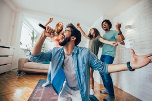 Group of friends playing karaoke at home
