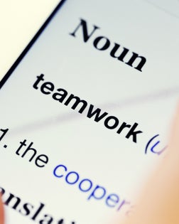 Fingers "pinch" online dictionary definition of teamwork on digital tablet