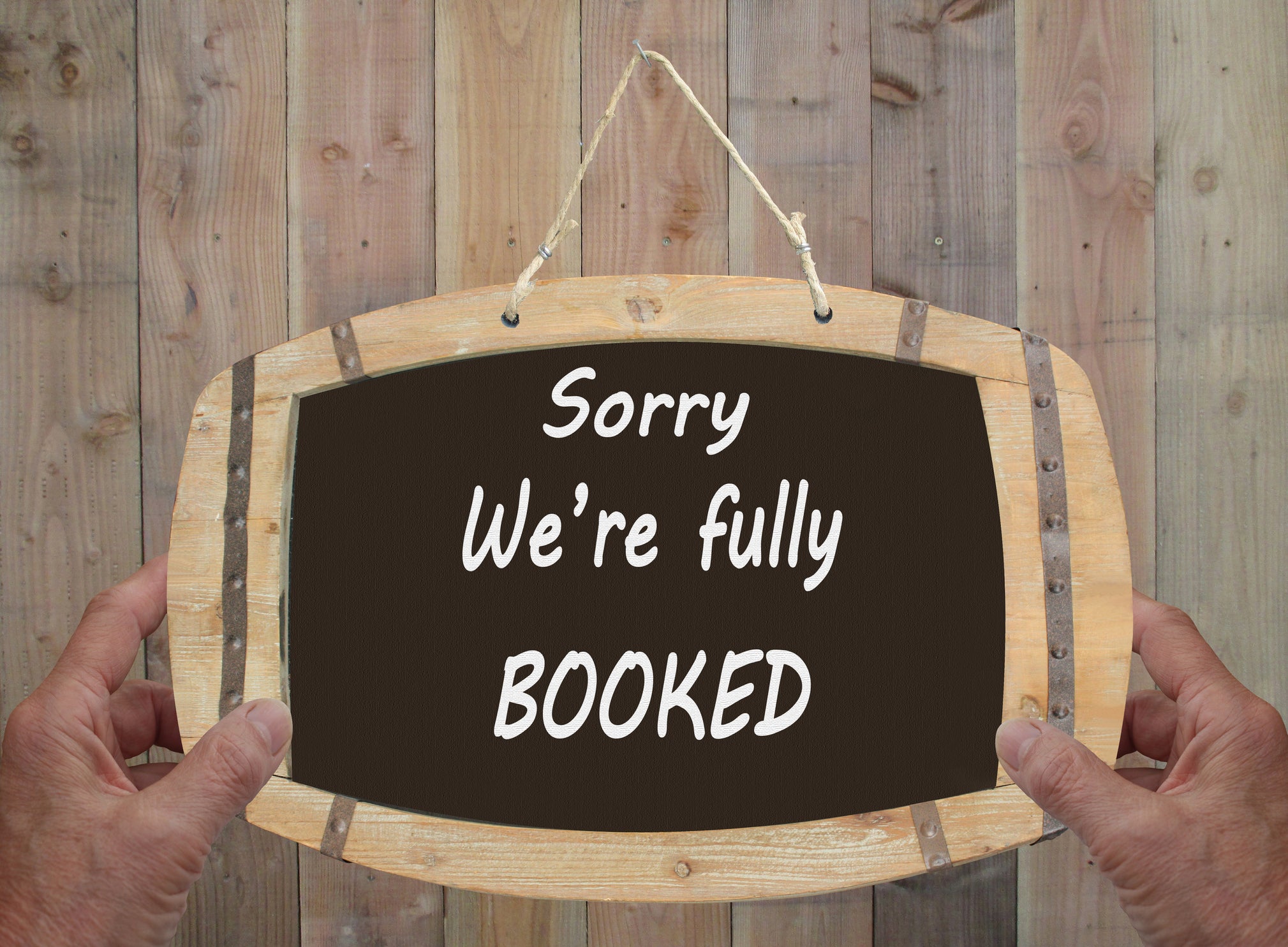 Message written in English on a slate hanging at the entrance of a hotel Sorry we 're fully  booked