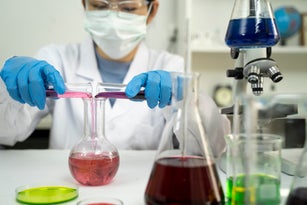 Female researcher pouring chemical into flask