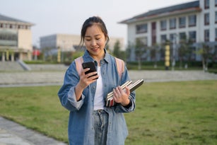A female college student uses her mobile phone on campus
