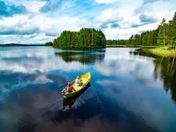 Aerial view of fishing boat with couple in blue summer lake in Finland