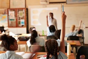 Girl raising hand and answering in classroom