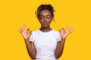 Peaceful african woman staying calm, meditating on yellow