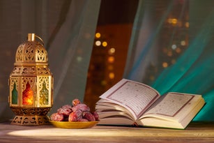 The Muslim feast of the holy month of Ramadan Kareem. The Holy Quran placed with Fanous and date fruits. Blurred background with beautiful lights