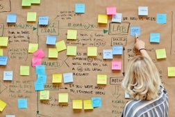 Businesswoman pointing at note on bulletin board