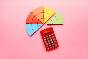High angle view of a pie chart made of colorful building blocks and red calculator on pink background
