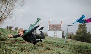 Comical, surreal image of a little boy, being blown away by a gust of wind