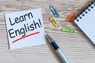 Learn english - note at wooden background with teachers glasses