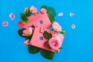 Retro cassette tapes with rose flowers and leaves on a vibrant blue background. Sounds of spring music concept with copy space.