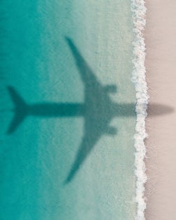 Aerial shot showing an aircraft shadow flying over an idyllic beach scene, Barbados