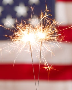 Bright burning sparklers against American flag, closeup