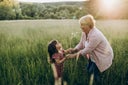 Grandmother and her little granddaughter walking in the field.