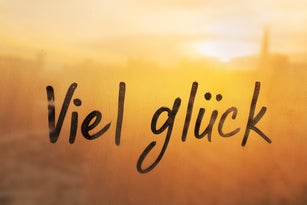 Lettering Deutsch language text Viel gluck is Good luck in english message written finger on foggy glass wet sunset window