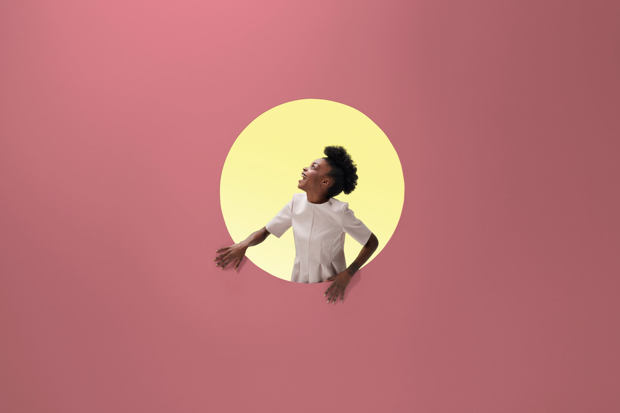 Woman laughing, placed inside round opening in coloured wall