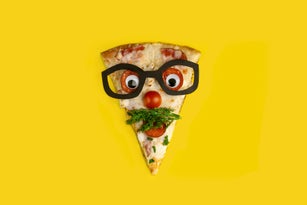 slice of pizza decorated as a surprised man in glasses on a yellow background