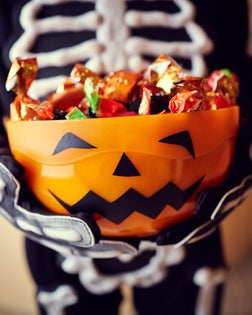 Boy in skeleton costume holding bowl full of candies