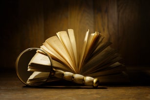 Magnifying glass in front of antique book with open pages. Old ancient open book.