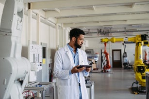 Serious robotic engineer, scientists checking data in tablet after experiment in modern robotics laboratory. Concept of robotics, engineering and computer science.
