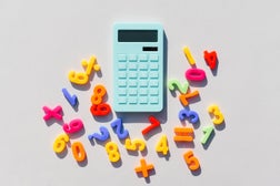 Blue calculator and math symbols on a universal gray background. Gray background. Blue calculator. Math symbols.