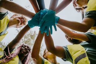 Volunteers wearing gloves bringing hands together