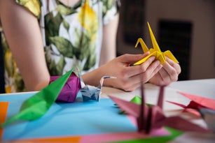 Teenager making a yellow origami paper crane