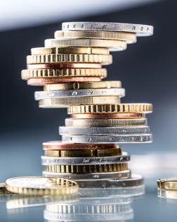 Euro coins built in the shape of a tower that balances before falling, a symbol of financial growth and fall - Close Up.
