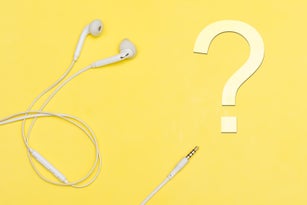 White headphones on a yellow background. Question mark. Concept creative