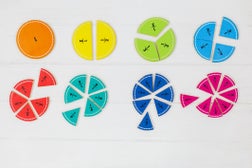 Multicolored fractions, blocks, notebook on white wooden table. Back to school, fun math, games for kindergarten, preschool education.