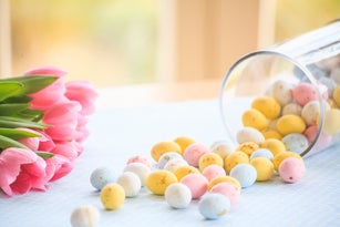 Easter eggs fallen from a glass jar and tulips bouquet