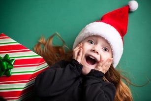 Excited Girl Wearing Santa Hat with Christmas Present