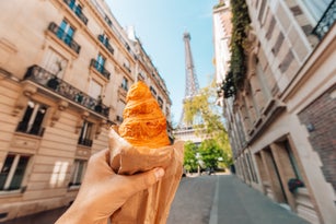 Man holding croissant next to Eiffel Tower, personal perspective view, Paris, France