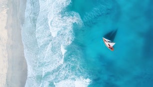 Yacht on the water surface from top view. Turquoise water background from top view. Summer seascape from air. Travel concept and idea
